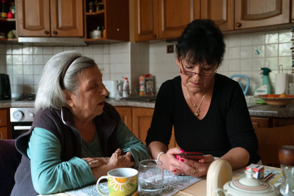Seniorka i opiekunka spędzają razem czas przy stole w domu
